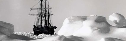 A black boat can be seen stuck within the white ice backdrop. The ice is undulating and tinged grey by shadows