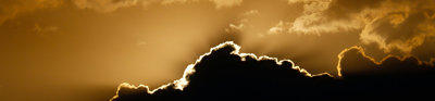 The sun is shining behind clouds, creating a golden effect in the sky.