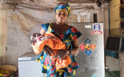 A local resident of the Nymanarr village in The Gambia posing in front of a fridge while holding a baby.