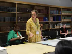 Dr Alice Oates gives a talk in the Foyle Reading Room during the map room conversations, she is showing the audience various maps on the table