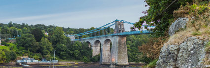 Blue bridge over water with rocks in the foreground