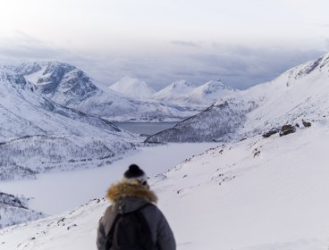 A person looking over a snowy scene of mountains and valleys