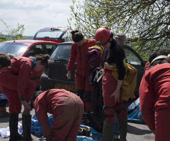 People wearing red caving gear and preparing for a descent
