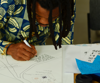 A person sitting at a table writing on a paper drawing