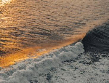 Waves at the shoreline with a sunset sky reflecting on the water