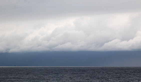 A seascape with white fluffy clouds over a grey sea