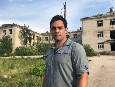 Ash standing outside of a derelict building