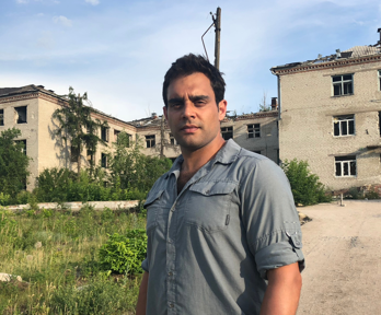 Ash standing outside of a derelict building