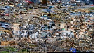 Houses destroyed and trees felled after a storm or tornado. Streets and gardens are filled with rubble and objects from the houses.