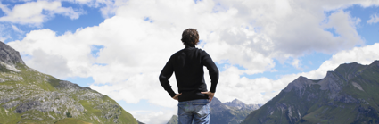 A man standing in the outdoors looking out over the Lake District, with mountains and valleys in the background