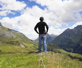 A man standing in the outdoors looking out over the Lake District, with mountains and valleys in the background