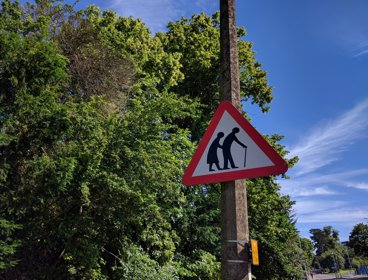 A red triangle road sign with two elderly people on it
