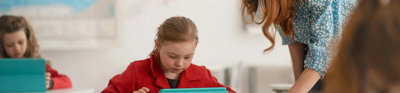 School pupil using a tablet with teacher supervising.