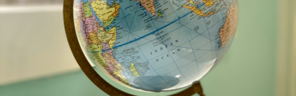 A globe sits on a white table next too a window. The background is blurred 