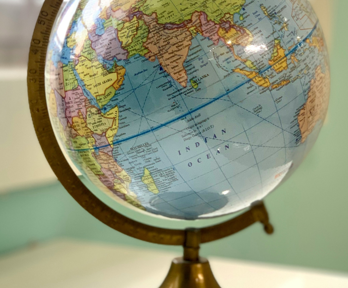 A globe sits on a white table next too a window. The background is blurred 