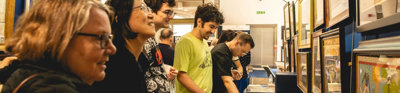 People at a map fair looking at maps disokated on tables.