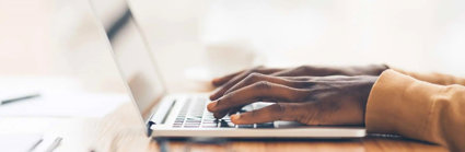 Closeup of a laptop and a person typing on the keyboard.