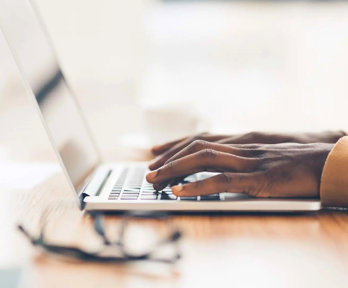 Closeup of a laptop and a person typing on the keyboard.