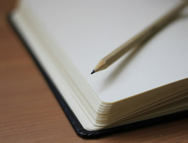 Close up of an open notebook with a pencil laying on top.