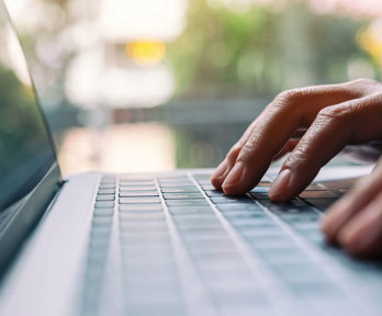 Closeup image of a person typing on laptop computer keyboard.