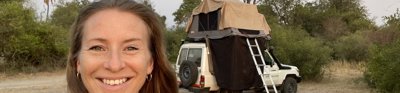 Charlotte standing in front of 4x4 vehicle with a tent on top