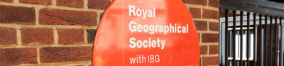 Large, round Royal Geographical Society with IBG entrance sign on a brick-wall.