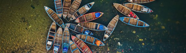 Traidtional Vietnamese wooden boats in the shape of a flower in a polluted sea and beach.