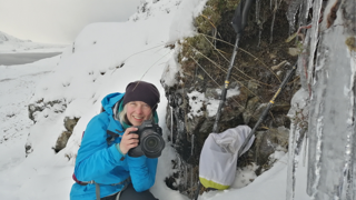 Phoebe Smith holding a camera in icy environment. 