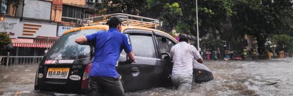 Two people moving a car through flood waters