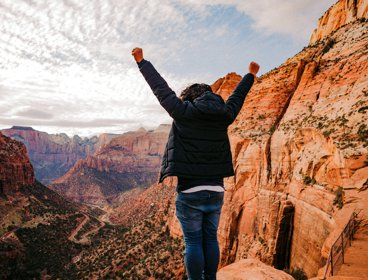 Person with hands in the air overlooking Grand Canyon