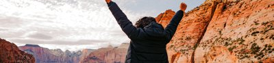 Person with hands in the air overlooking Grand Canyon