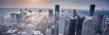 Drone view of city skyscrapers with low clouds between the buildings.