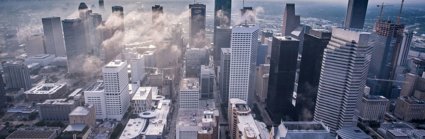 Drone view of city skyscrapers with low clouds between the buildings. 