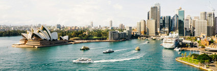 A skyline view of Sydney, Australia, as seen from the sea, showing boats and the Sydney Opera House.