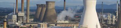 An aerial view of a power station, showing chimneys and smoke