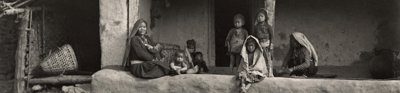 Black and white image of adults and children sat outside a typical Limbu house in Eastern Nepal. Photographer: C.J.Morris, 1926
