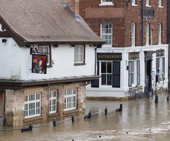 Flooded street with water rising towards windows of brick buildings. 