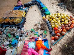 Earth Photo 2023 entry combing the sea, combing peace. Two young people lie amongst sand and plastic from the ocean.