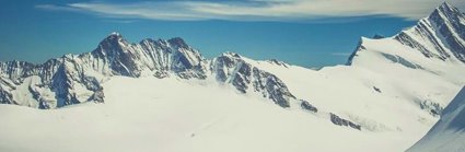 A snow covered glacier with the tips of mountains poking through the snow and ice