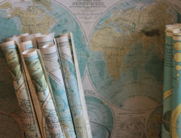 Map scrolls leaning up against a backdrop of another map