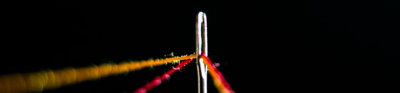 Strings of yellow and red thread in needle against black background.