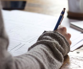 Person holding a pen and writing on a piece of paper