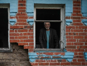 Person looking out of war damaged building in Ukraine