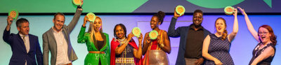 People on stage holding up medals in celebration at an awards ceremony. 
