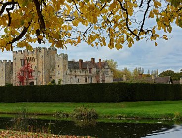 Hever Castle with a moat in front of it in autumn.