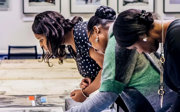 Three people looking at artefacts laid out on a table in the Foyle Reading Room.