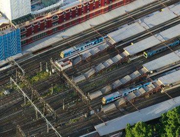 Aerial view of a train station, with trains stationary at the platforms. 