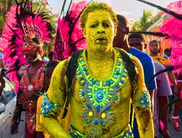 A man at mardi gras covered in colourfuul body paint