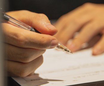 Person writing with a pen on paper.