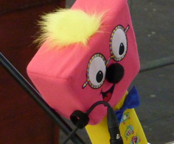Timmy Mallet's mallet, a pink and yellow soft toy in the shape of a mallet with eyes, nose and mouth and glasses to look like the face of Timmy Mallet